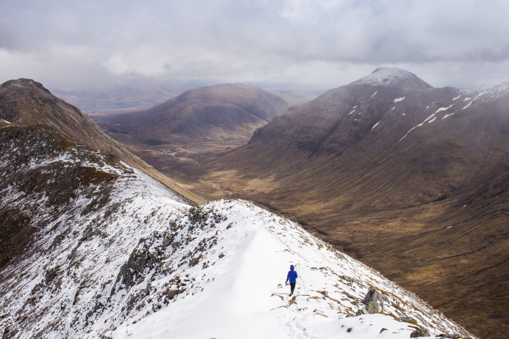 A person walking on a light dusting of snow in Glencoe Scotland