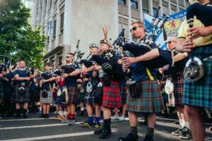 Tartan Army bagpipers march down a street in Boston